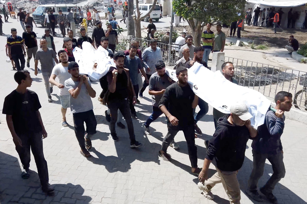 Palestinians inside Gaza's Ahli Hospital carrying the bodies of relatives killed in Israeli airstrikes.
